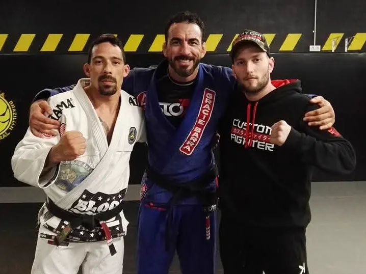Alejandro Tebar y otros dos deportistas en el tatami de una academia de jiu-jitsu brasileño. Dos llevan kimono.